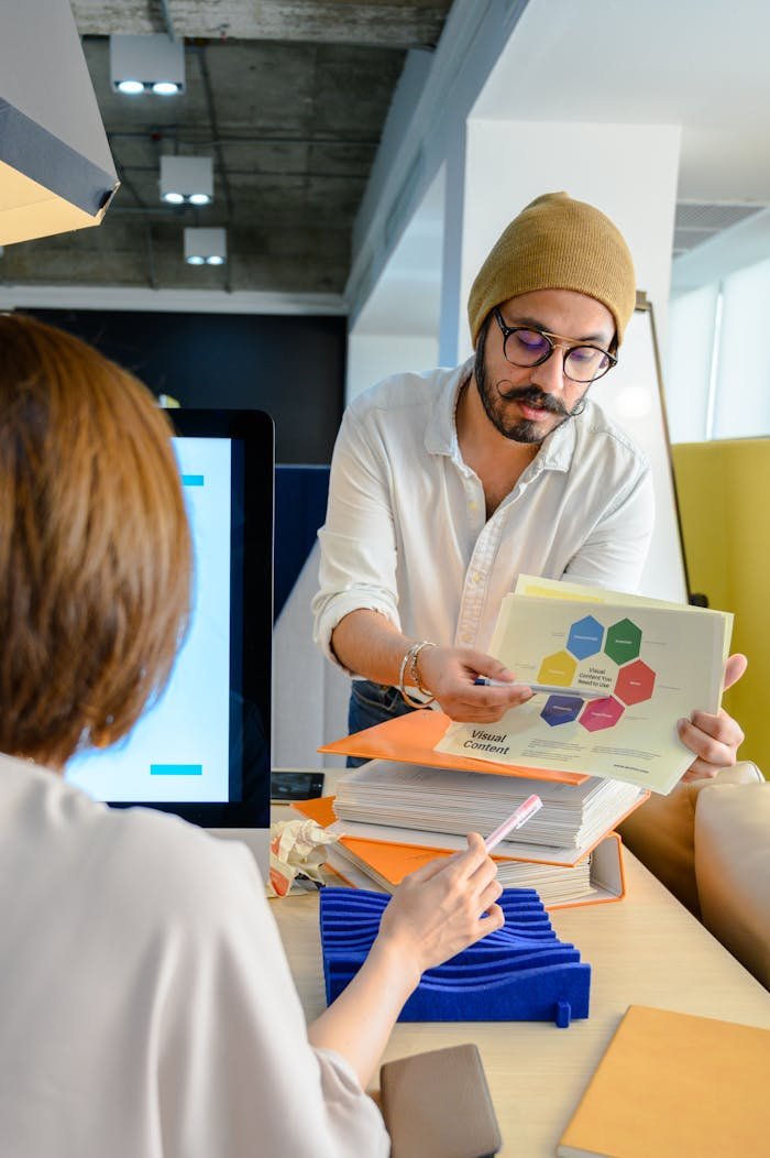 Bearded man discussing business strategy with colleague in a modern office environment.